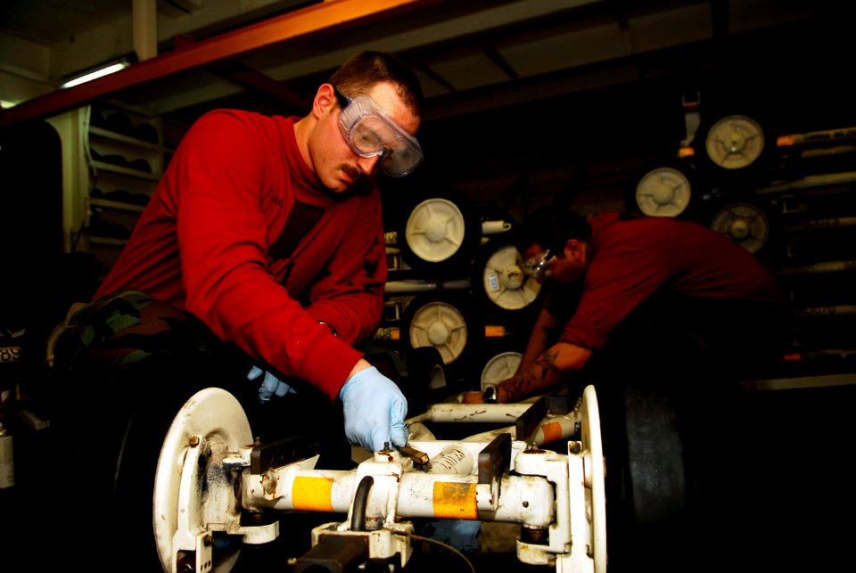 US Navy 090226-N-2475A-091 Aviation Ordnanceman 3rd Classes Steven Fine, left, from Ogden, Utah, and Christopher Mundell, from Pittsburgh, perform corrosion control on an MHU-191 munitions skid