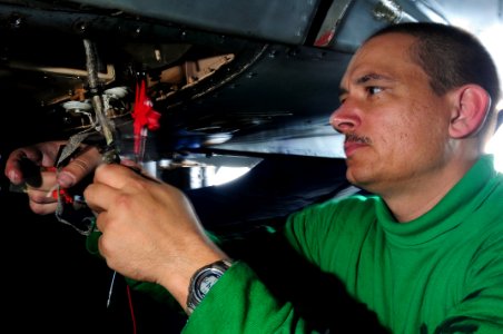 US Navy 090227-N-3946H-053 Aviation Electrician's Mate 1st Class David Summers troubleshoots the wiring of a generator cannon plug