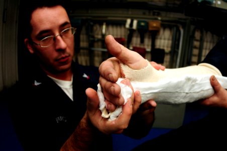 US Navy 090228-N-9760Z-002 Hospital Corpsman 3rd Class Christopher Buis molds cast to a patient's arm