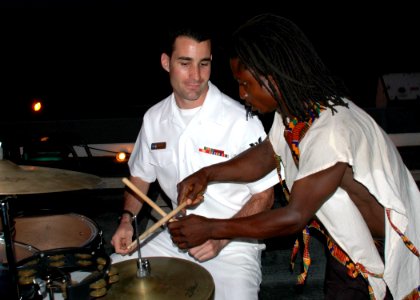 US Navy 090227-N-1655H-352 Musician 2nd Class Ross Hartig, assigned to the Commander, U.S. Naval Forces Europe Band, and a Ghanaian drummer compare notes during a reception for Ghanaian distinguished visitors aboard the amphibi