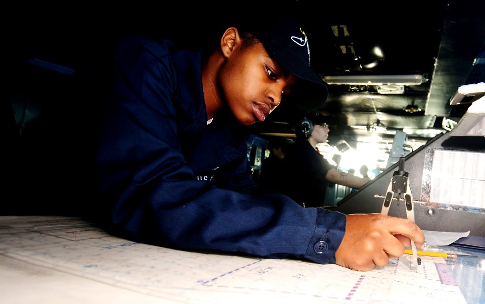 US Navy 090305-N-9760Z-001 Quartermaster Seaman Recruit Kabresha Richardson plots the position of the nuclear-powered aircraft carrier USS Nimitz (CVN 68) on charts in the ship's Pilot House