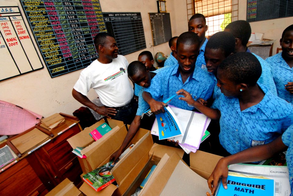 US Navy 090304-N-1688B-335 Cameroon Navy Lt. Cmdr. Hamadou Lame, left, watches as students from the Naval Base Basic School in Sekondi, Ghana receive school books and supplies donated by Project Handclasp