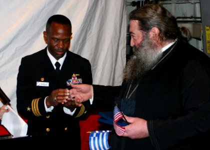 US Navy 090303-N-6764G-113 Bishop Polykarpos presents a gift to Cmdr. Eric Cash, commanding officer of the amphibious transport dock ship USS San Antonio (LPD 17), during a reception for visitors from Santorini, Greece