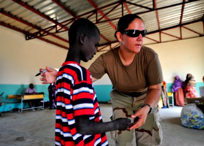 US Navy 090308-N-0506A-222 Interior Communications Electrician 1st Class Kimberly Allen, assigned to Combined Joint Task Force-Horn of Africa, marks the hands of a boy to identify him as having received a dose of the de-worming photo