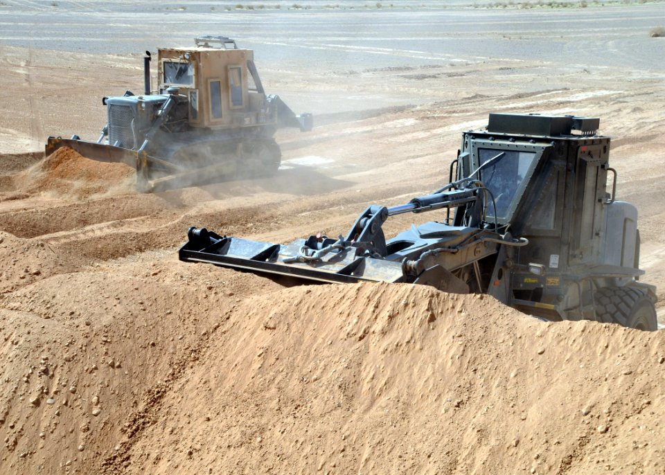 US Navy 090305-N-1120L-078 Seabees assigned to Naval Mobile Construction Battalion (NMCB) 7 use an up-armored bulldozer and front end loader to build protective berms for a forward operating base