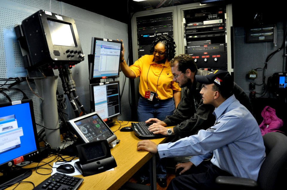 US Navy 090310-D-5972N-004 Civilian employees work with Information Systems Technician 2nd Class James Rago to troubleshoot the video teleconference system of a video information exchange system