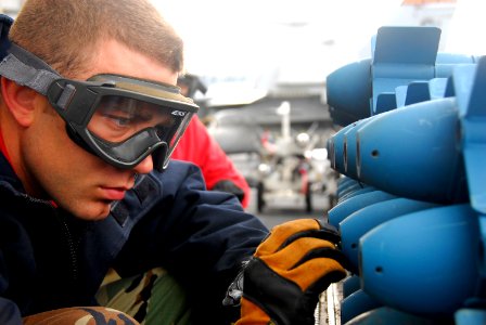 US Navy 090304-N-6597H-093 Aviation Ordnanceman Airman Mark Mills, from Chicago, arms MK-76 practice bombs aboard the Nimitz-class aircraft carrier USS John C. Stennis (CVN 74)