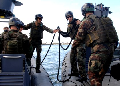 US Navy 090305-N-5366K-145 A Special Warfare Combatant-craft Crewman candidate passes a tow-line to an assisting rigid-hull inflatable boat crew photo