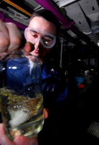 US Navy 090317-N-6597H-015 Aviation Boatswain's Mate (Fuel) 3rd Class Justin Cox, from Muncie, Ind., checks the purity of fuel in the aft aviation fuels pump room aboard the aircraft carrier USS John C. Stennis (CVN 74)
