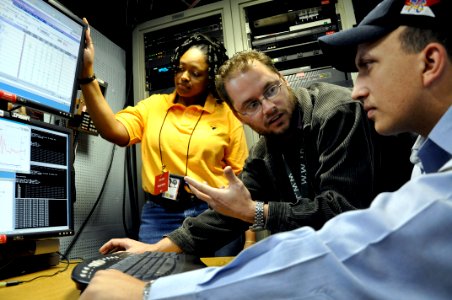 US Navy 090310-D-5972N-002 Civilian employees work with Information Systems Technician 2nd Class James Rago to troubleshoot the video teleconference system of a video information exchange system