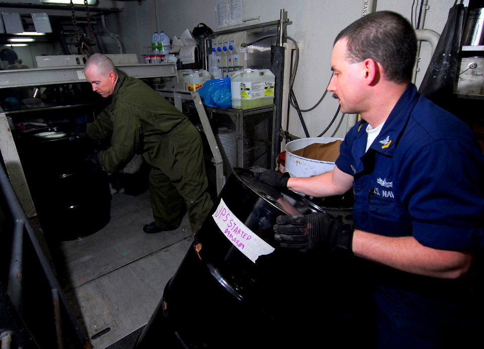 US Navy 090316-N-6597H-075 Boatswain's Mate 2nd Class George Cabeen and Machinist's Mate 2nd Class Martin Davidson moves drums of hazardous material onto a lift