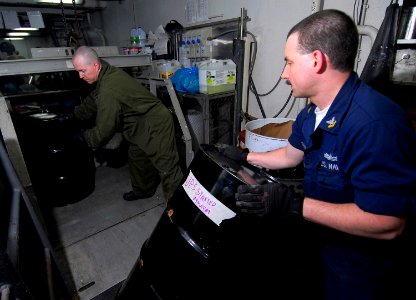 US Navy 090316-N-6597H-075 Boatswain's Mate 2nd Class George Cabeen and Machinist's Mate 2nd Class Martin Davidson moves drums of hazardous material onto a lift