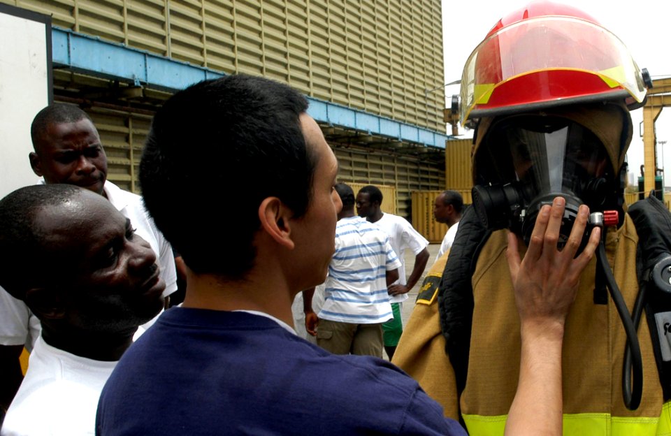 US Navy 090320-N-3316L-107 Damage Controlman 3rd Class Victor Rodriguez, assigned to the amphibious transport dock ship USS Nashville (LPD 13), checks the seal on the self-contained breathing apparatus of a member of the Nigeri