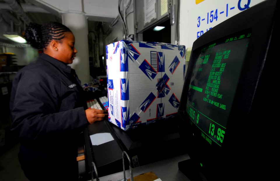 US Navy 090315-N-6597H-203 ostal Clerk 3rd Class Donysha Rochester calculates postage for a package