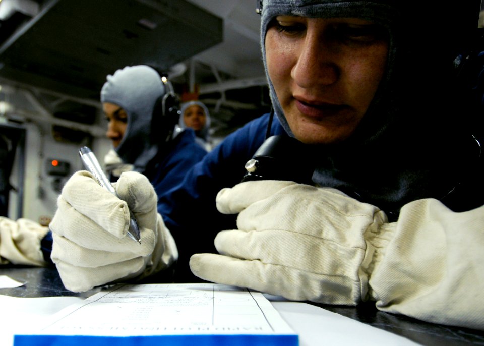 US Navy 090323-N-7478G-055 Mass Communication Specialist 3rd Class Daniel Viramontes writes down a message while communicating on a sound-powered phone in Damage Control Central