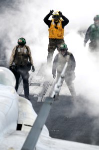US Navy 090320-N-3659B-067 Aviation Boatswain's Mate (Handling) Airman Daryl Cobb uses hand signals to tell the pilot of an F-A-18C Hornet to move the aircraft forward onto catapult one