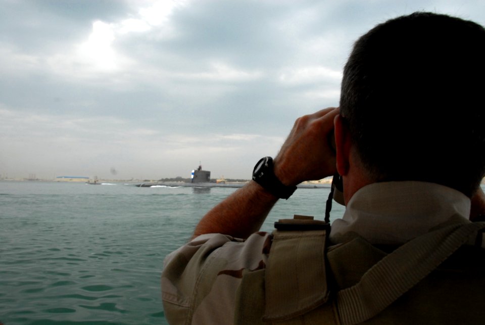 US Navy 090321-N-9909C-152 Vice Adm. Bill Gortney watches through binoculars as the Los Angeles-class attack submarine USS Hartford (SSN 768) transits into Mina Salman pier in Bahrain