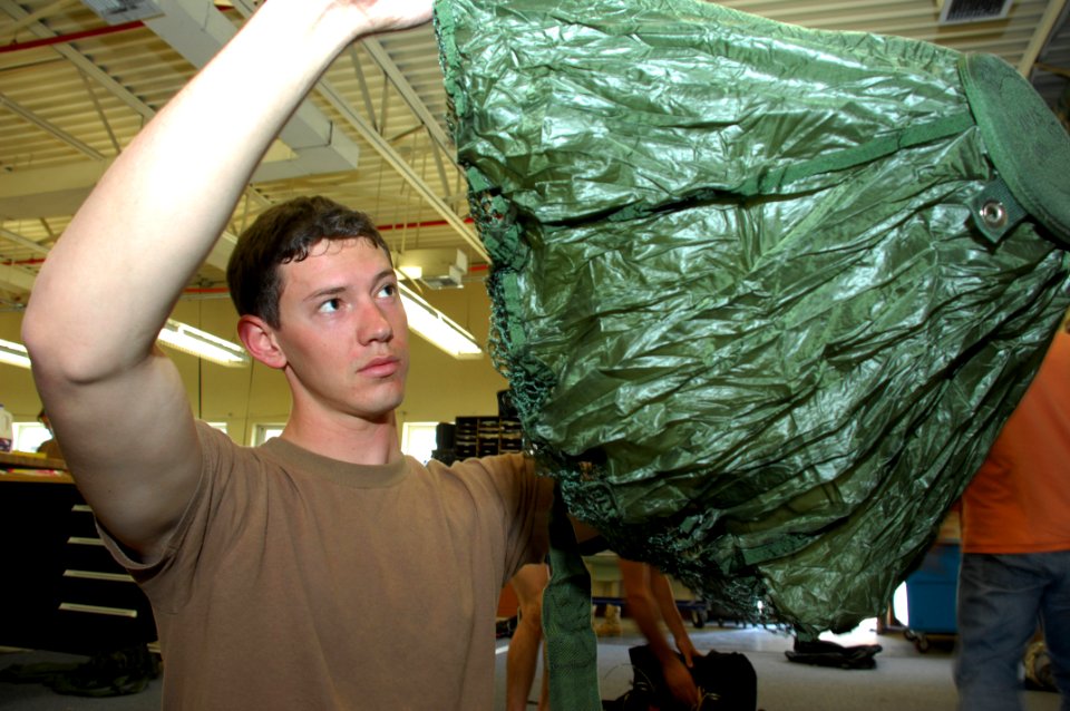 US Navy 090327-N-5366K-018 Aircrew Survival Equipmentman 2nd Class Christopher Allen inspects a reserve pilot parachute for holes and tears