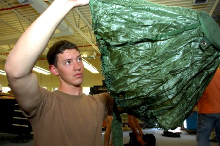 US Navy 090327-N-5366K-018 Aircrew Survival Equipmentman 2nd Class Christopher Allen inspects a reserve pilot parachute for holes and tears photo