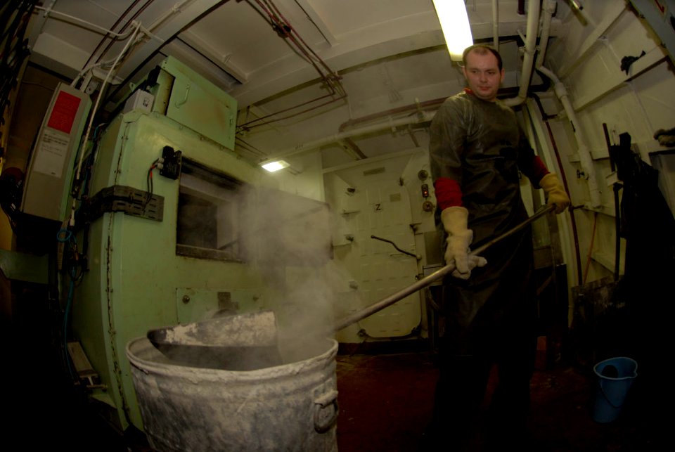 US Navy 090327-N-2475A-035 Aviation Ordnanceman Airman Matthew Bartram, from Kansas City, Kan., empties ashes from the incinerator aboard the Nimitz-class aircraft carrier USS John C. Stennis (CVN 74)