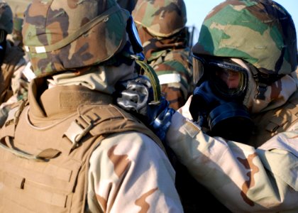 US Navy 090325-N-4973M-008 Lt. Cmdr. Ferdinand Herrera fastens a chemical, biological, and radiological suit for Culinary Specialist 1st Class Victor Rojas during a recent Amphibious Construction Battalion (ACB) 1 field exercis photo