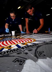 US Navy 090326-N-6597H-012 Seaman Courtney Alumbaugh, left, from Great Lakes, Ill., and Boatswain's Mate Seaman Alex Chetwood, from Cedar Grove, Ind., repaint the command seal on the deck in the forecastle