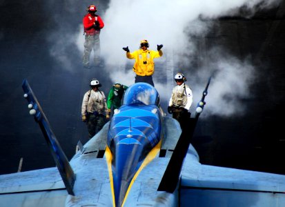 US Navy 090328-N-6597H-427 A flight deck director gives hand signals to the pilot of an F-A-18C Hornet from the