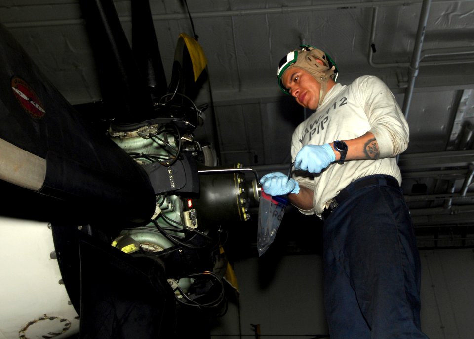 US Navy 090328-N-0096C-004 Aviation Machinist's Mate Airman Juan Guzman, from Los Angeles, removes bolts from a propeller on an E-2C Hawkeye assigned to the