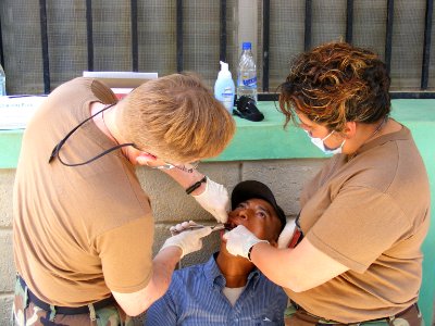 US Navy 090401-N-1580K-582 Navy dentist Cmdr. David Reiter and Hospital Corpsman 2nd Class Amy Brown remove an upper molar from a villager in Aguacatal during the Beyond the Horizon humanitarian assistance exercise in Honduras photo