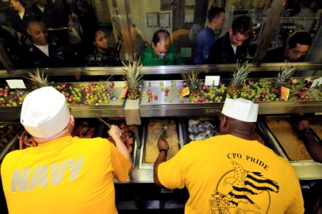 US Navy 090401-N-5758H-059 Master Chief Master-at-Arms Paul Bettis, left, and Master Chief Aviation Maintenance Administrationman Leonard Gage serve meals to crew members aboard the aircraft carrier USS Dwight D. Eisenhower (CV