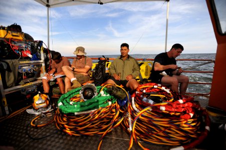 US Navy 090329-N-5242D-221 Navy Diver 1st Class Nicholas Holmes, Chief Navy Diver Jason Potts, Senior Chief Navy Diver Jorge Guillen and Master Chief Navy Diver Arne Phillips relax and eat after a long day of dives in Africa's