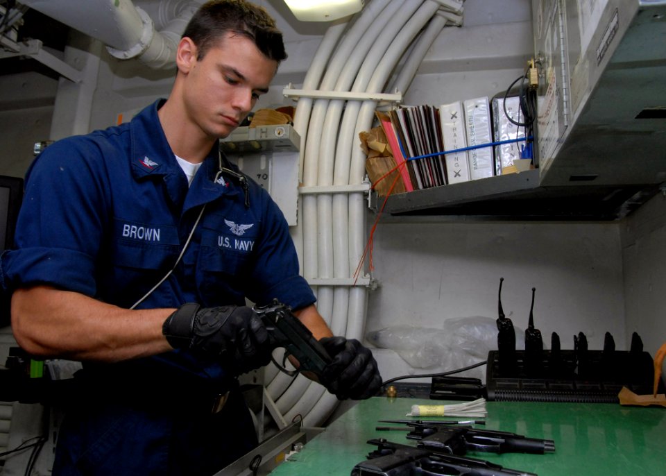 US Navy 090327-N-8283S-003 Gunner's Mate 3rd Class Erik Brown, from Coco Beach, Fla., breaks down a 9mm M9 Beretta service pistol for cleaning after a small arms live-fire exercise aboard the amphibious assault ship USS Boxer (