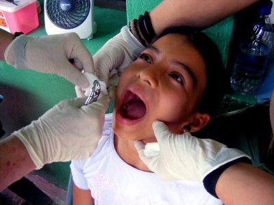 US Navy 090331-N-1580K-379 Dentist Cmdr. David Reiter and Hospital Corpsman 2nd Class Amy Brown prepared to remove a molar from 11-year old Isabel during the Beyond the Horizon humanitarian exercise in Honduras photo