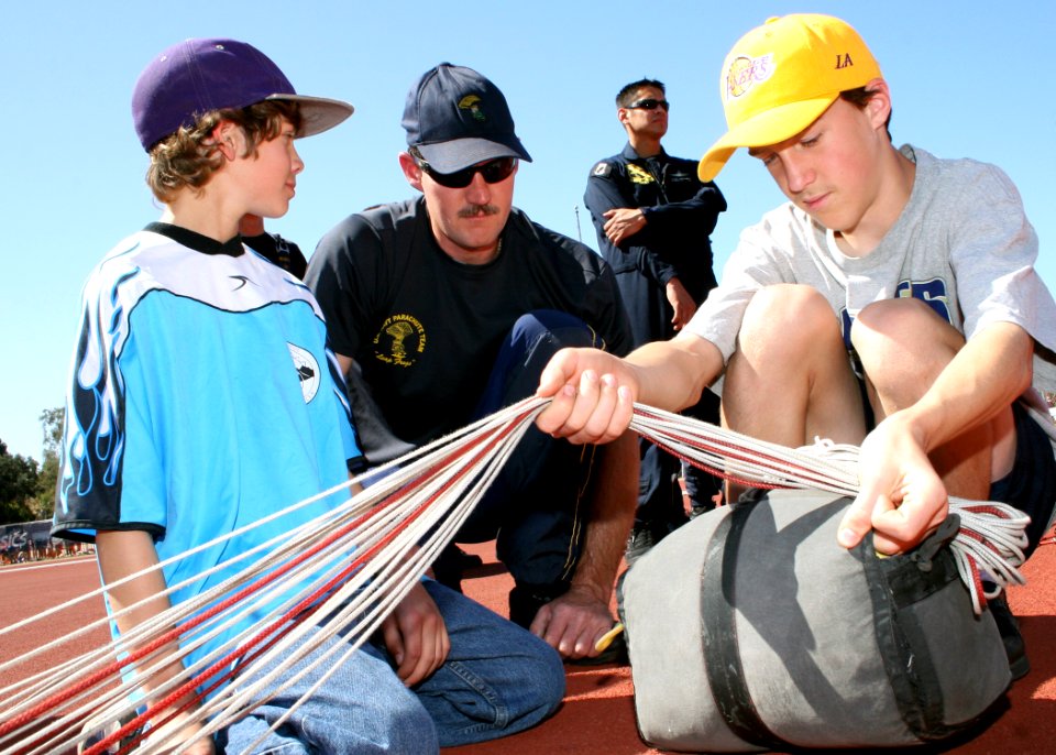 US Navy 090328-N-5366K-015 Chief Special Warfare Operator (SEAL) William Davis, assigned to the U.S. Navy Parachute Team, shows two children how to pack his parachute at Mount Carmel Invitational Track and Field