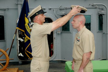 US Navy 090401-N-6410J-088 Master Chief Damage Controlman Mark Geer removes Chief Machinist's Mate Kelly King's chief combination cover during King's commissioning ceremony aboard the amphibious assault ship USS Boxer (LHD 4)