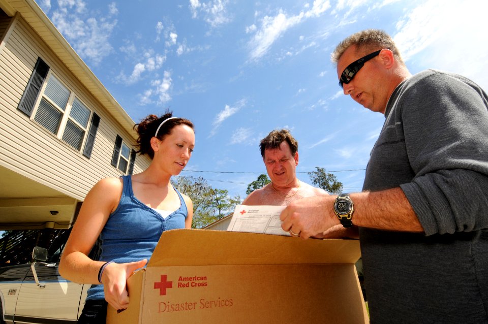 US Navy 090404-N-5328N-093 Candace Nordin, left, and her father, Ken Nordin listen as Chief Information Systems Technician Ron Clement explains the contents of an American Red Cross cleanup kit and how to use the supplies