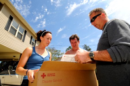 US Navy 090404-N-5328N-093 Candace Nordin, left, and her father, Ken Nordin listen as Chief Information Systems Technician Ron Clement explains the contents of an American Red Cross cleanup kit and how to use the supplies