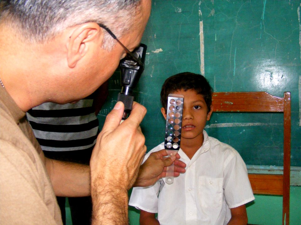 US Navy 090402-N-1580K-710 Navy optometrist Cmdr. Louis Perez uses a retina scope and lens rack to check the eyes of 9-year old Sergio Colochos during the Beyond the Horizon humanitarian assistance exercise in Honduras