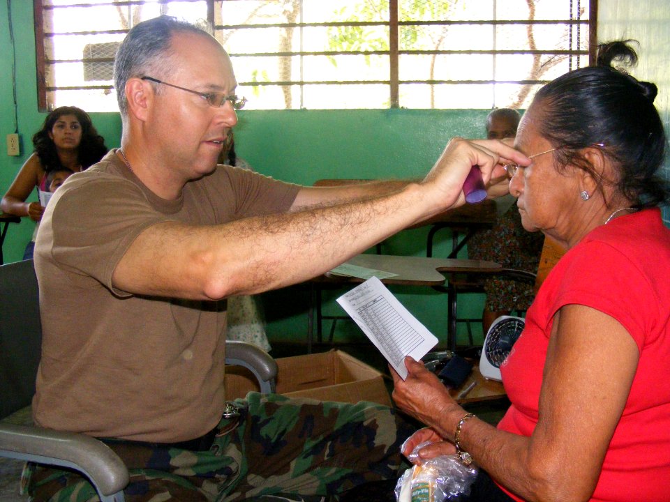 US Navy 090402-N-1580K-690 Navy optometrist Cmdr. Louis Perez adjusts a new set of reading glasses on 71-year old villager Marcelina Martinez during the Beyond the Horizon humanitarian assistance exercise in Honduras photo