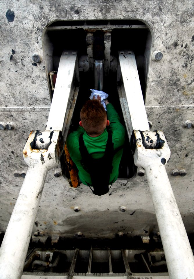 US Navy 090407-N-6538W-025 Aviation Boatswain's Mate Airman Oscar Auten, from Council Bluffs, Iowa, wipes down the hydraulic piston of a jet-blast deflector on the flight deck of the Nimitz-class aircraft carrier USS John C. St