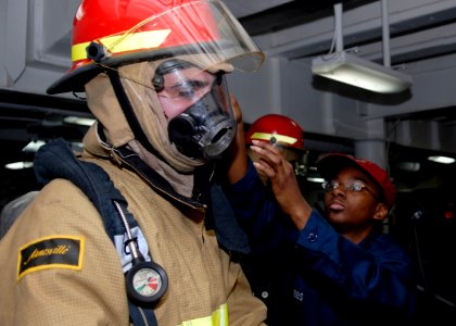 US Navy 090410-N-9520G-047 Information Systems Technician 2nd Class Shana Gibbs, from Chicago, Ill., adjusts a Sailor's firefighting gear during a general quarters drill