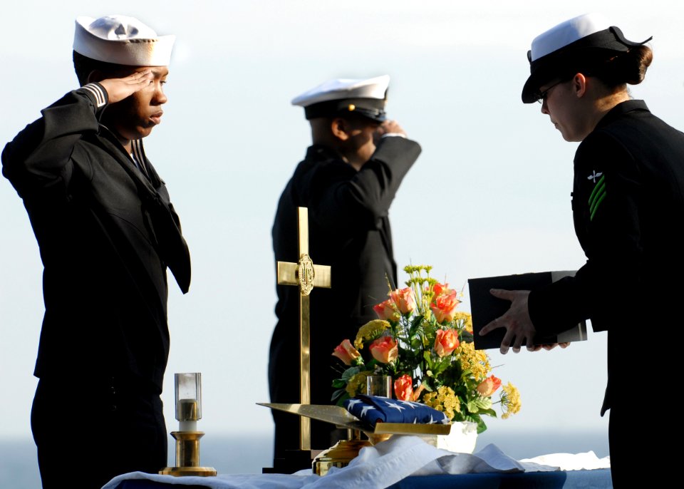 US Navy 090405-N-9950J-038 Aviation Maintenance Administrationman 3rd Class Fred Banks salutes as Aviation Machinist's Mate Tiffany Roach prepares to present cremains to Capt. Brent Canady during a burial at sea ceremony
