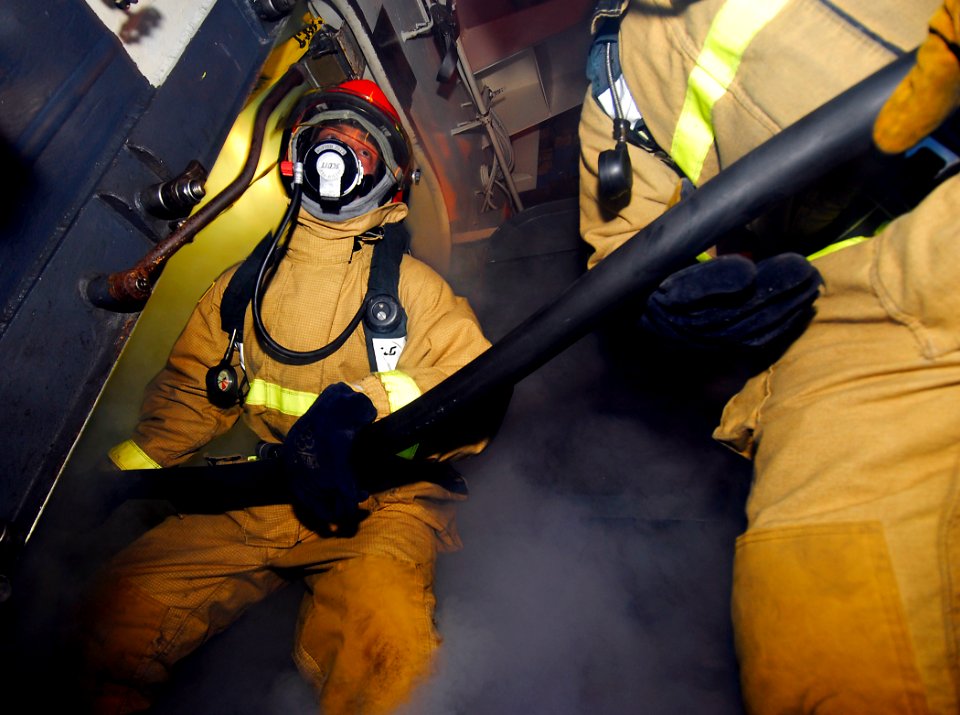 US Navy 090407-N-6597H-526 Sailors enter a smoky space to combat a simulated fire during a general quarters drill aboard the Nimitz-class aircraft carrier USS John C. Stennis (CVN 74)