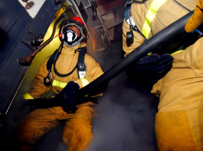 US Navy 090407-N-6597H-526 Sailors enter a smoky space to combat a simulated fire during a general quarters drill aboard the Nimitz-class aircraft carrier USS John C. Stennis (CVN 74)