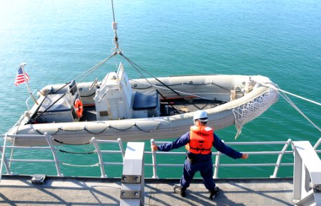 US Navy 090416-N-3666S-038 A Sailor gives directions as a rigid hull inflatable boat is raised onto the boat deck of the guided-missile frigate USS Reuben James