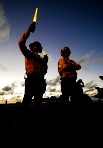 US Navy 090418-N-6538W-232 Aviation Boatswain's Mate (Handling) Airman Richard Koller and Aviation Boatswain's Mate (Handling) 3rd Class Matthew Mancebo direct aircraft on the flight deck during night flight operations