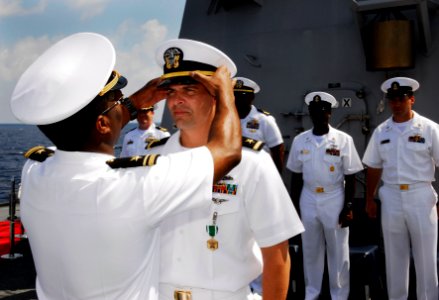 US Navy 090420-N-9928E-160 Lt. j.g. Adam Chambers, from Charleston, N.C., places an officer cover on Ensign Jean-Paul Bertram, from Vancouver, Canada, during Bertram's commissioning ceremony