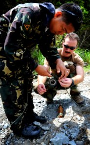 US Navy 090422-N-7130B-108 Explosive Ordnance Disposal Technician 2nd Class Travis Becker helps a member of the Armed Forces of the Philippines Army Explosive Ordnance Disposal Battalion tape together two pieces of detonation c photo