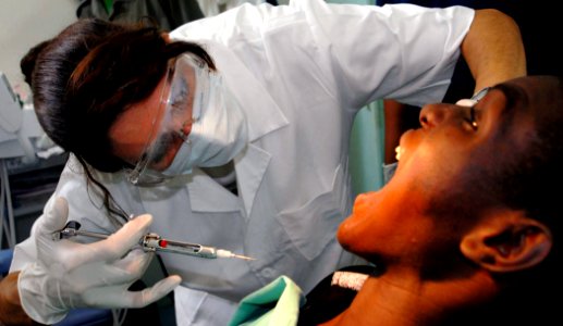 US Navy 090421-N-1688B-039 Lt. Cmdr. Shay Razmi, a dental officer embarked aboard the amphibious transport dock ship USS Nashville (LPD 13), administers Novocain to a patient before extracting a tooth during an Africa Partnersh