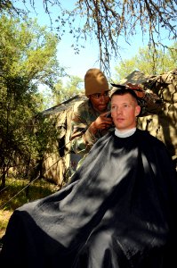 US Navy 090420-N-9584H-074 Ships Serviceman 3rd Class Cedric Obryant, assigned to Naval Mobile Construction Battalion (NMCB) 3, gives a haircut ot Lt. Aaron Ripple photo